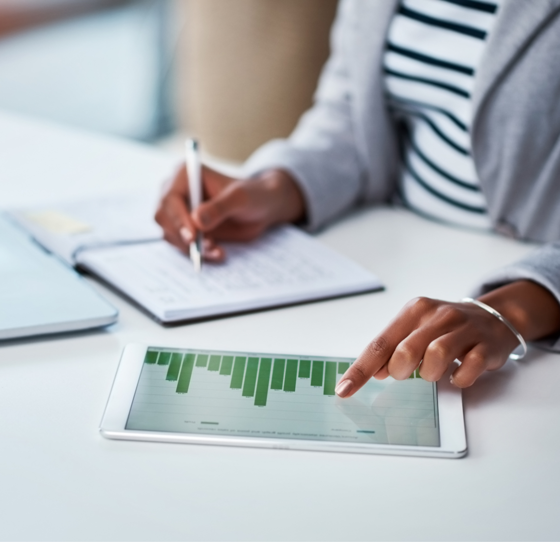 lady writing and looking at ipad
